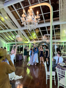 family-dancing-in-room-with-hanging-chandeliers-and-green-uplights