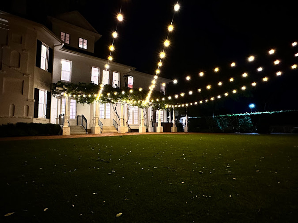 string-lights-expanding-across-yard-in-front-of-yellow-old-home