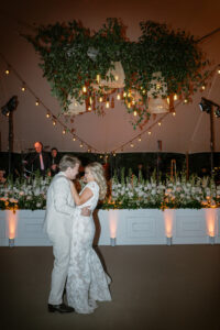 orange-uplights-with-bride-and-groom-dancing-in-front-of-floral-display